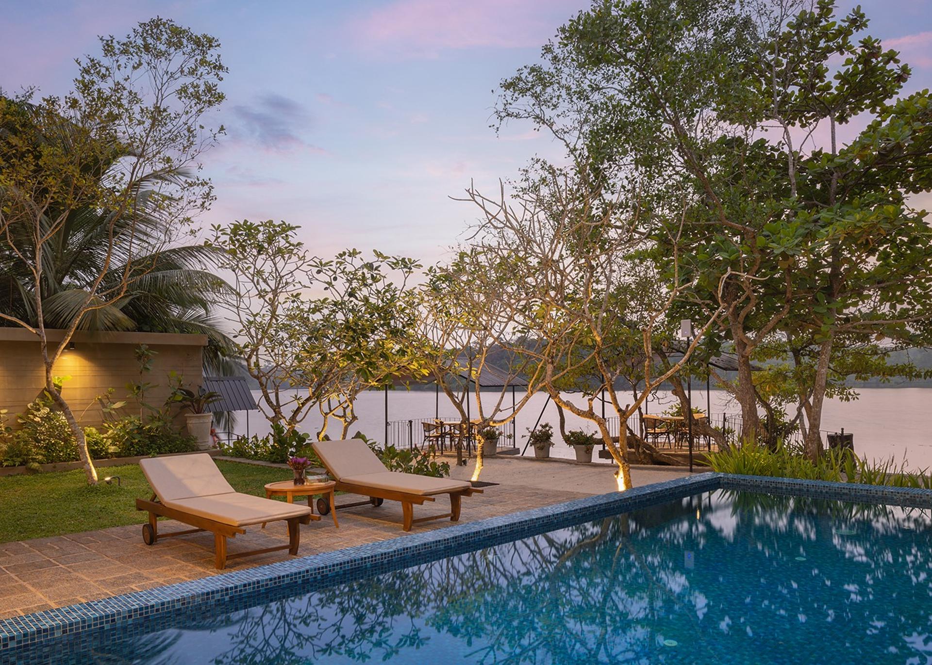 Yahva Bentota villa pool deck with sun loungers at sunset beside Dedduwa Lake