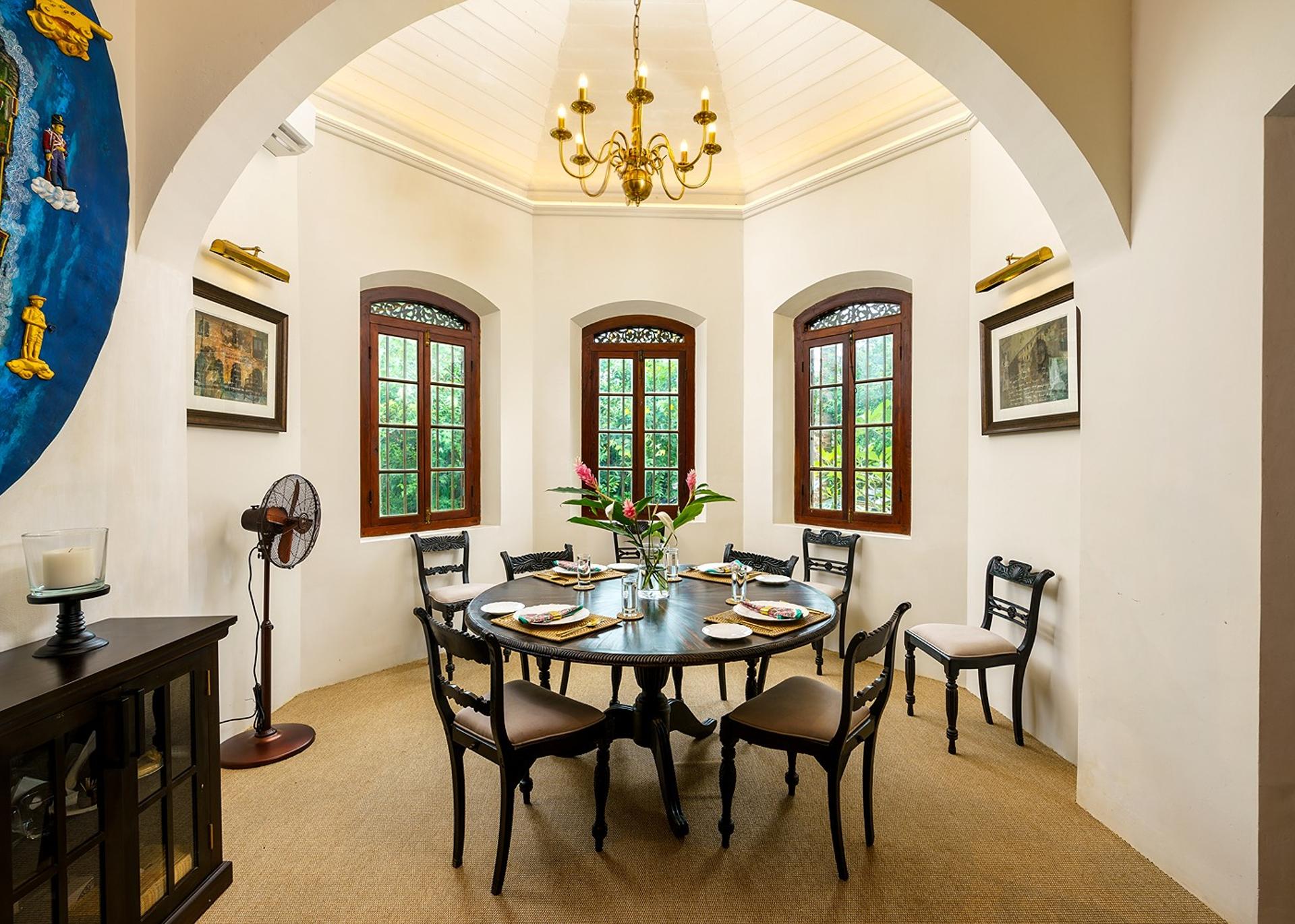 Elliot House Galle dining room with brass chandelier, round table and original art