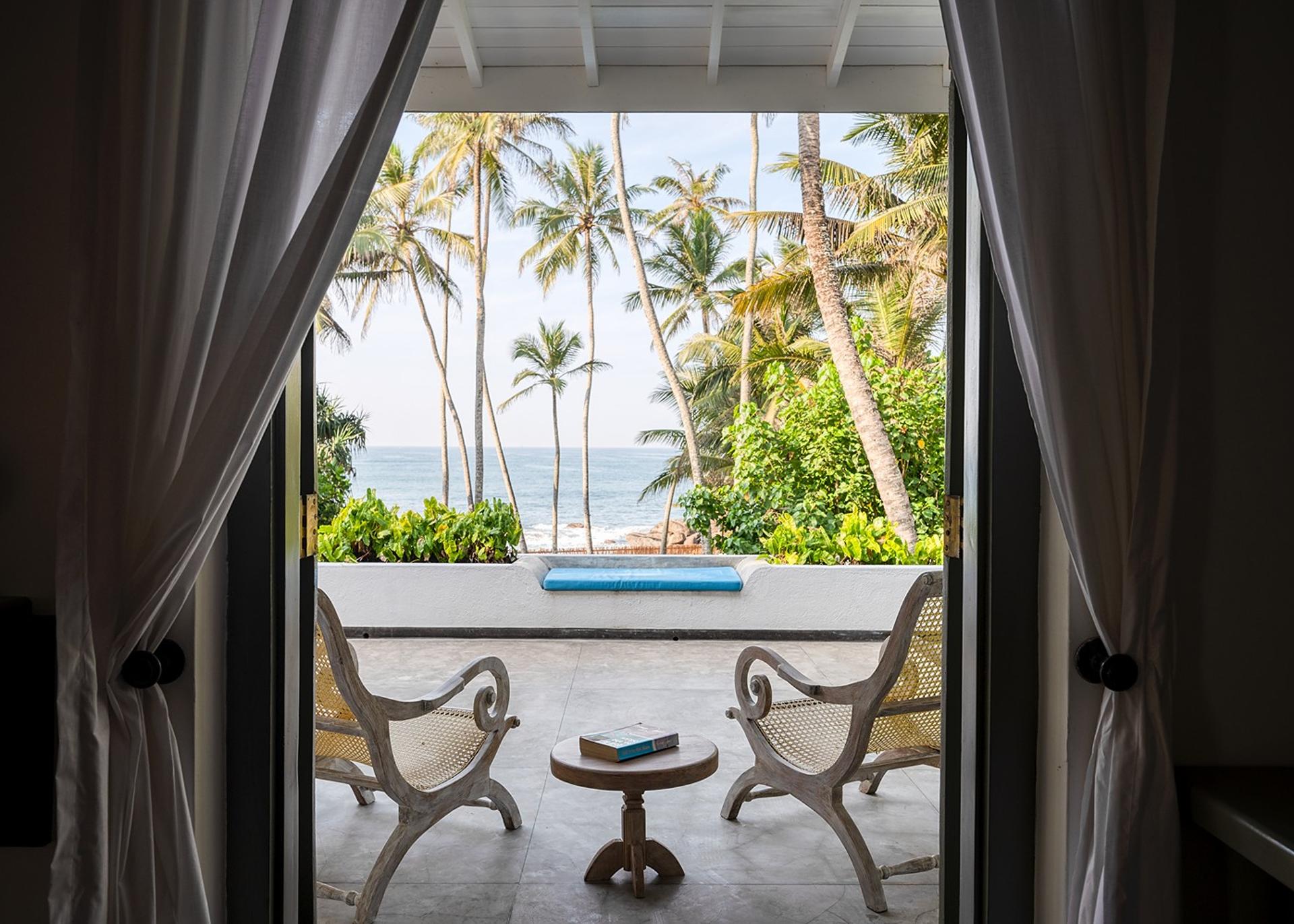Beachfront villa bedroom with ocean view balcony and billowing curtains Unawatuna
