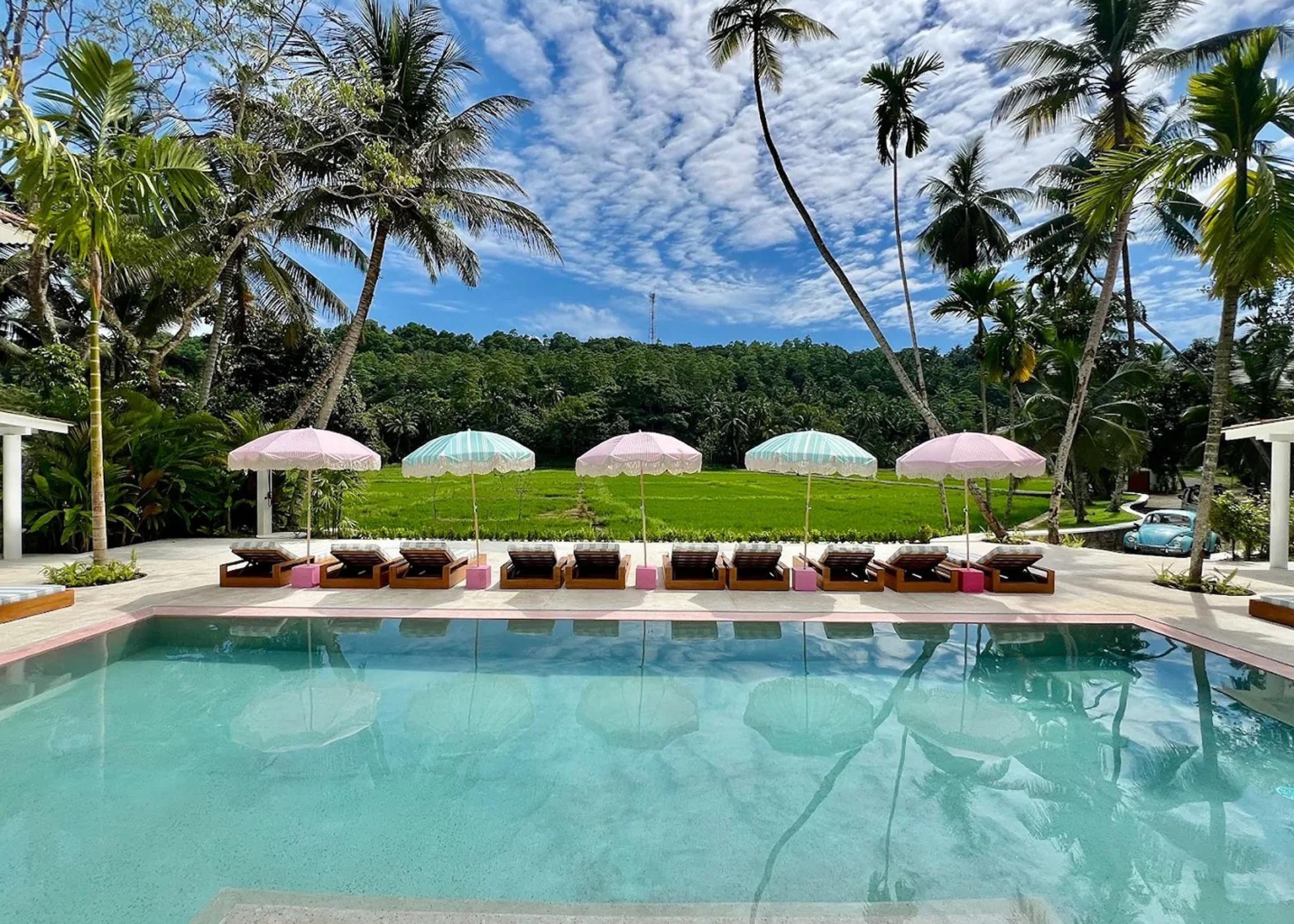 Miss Ceylon Unawatuna pool with sun loungers and tropical garden under blue sky