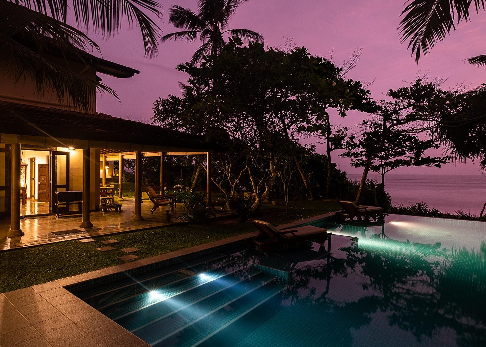 Villa Tres Matara infinity pool illuminated at evening with pink sky