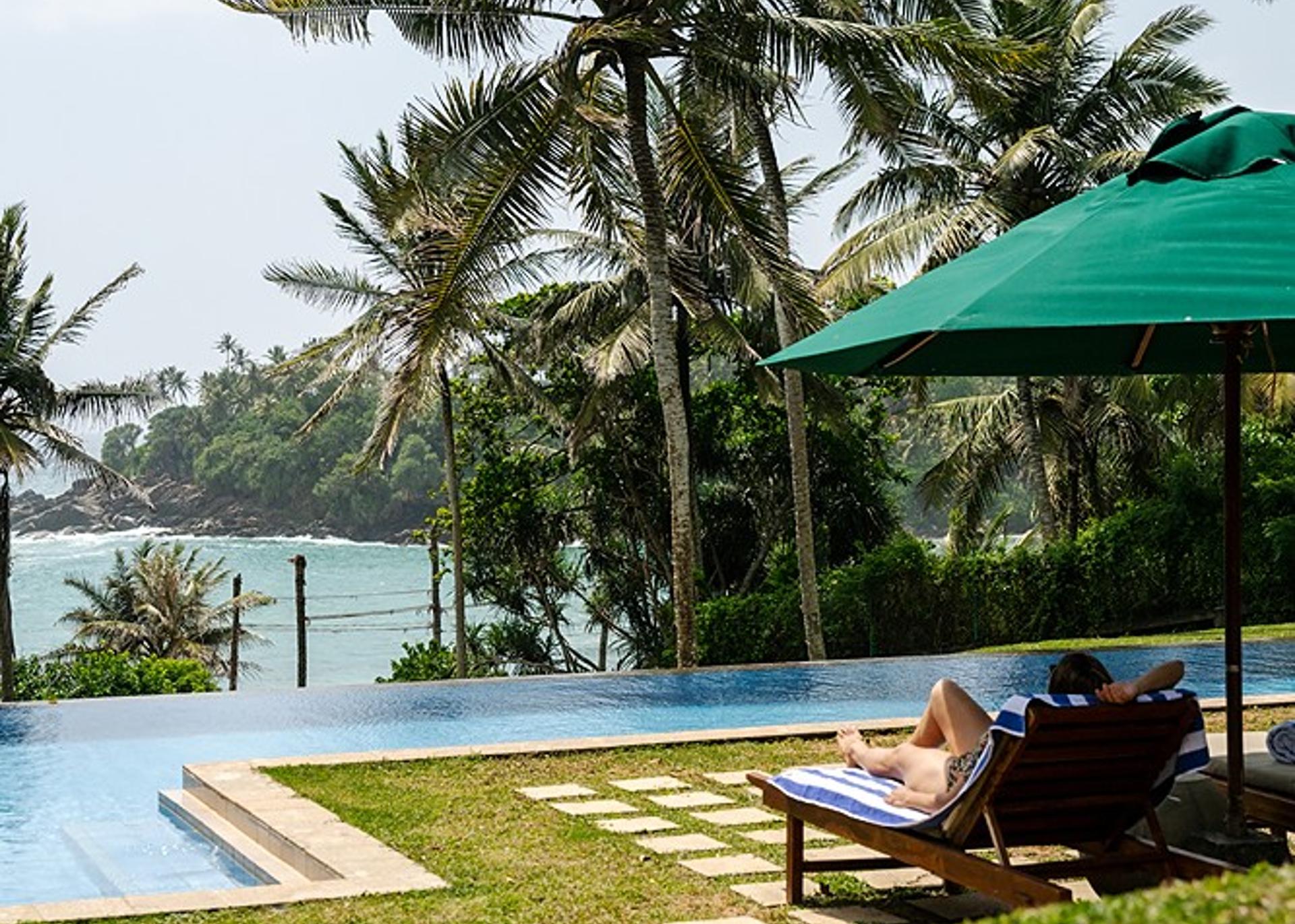 Wide-angle view of the expansive garden at Pavana Hiriketiya with towering palm trees and manicured lawn