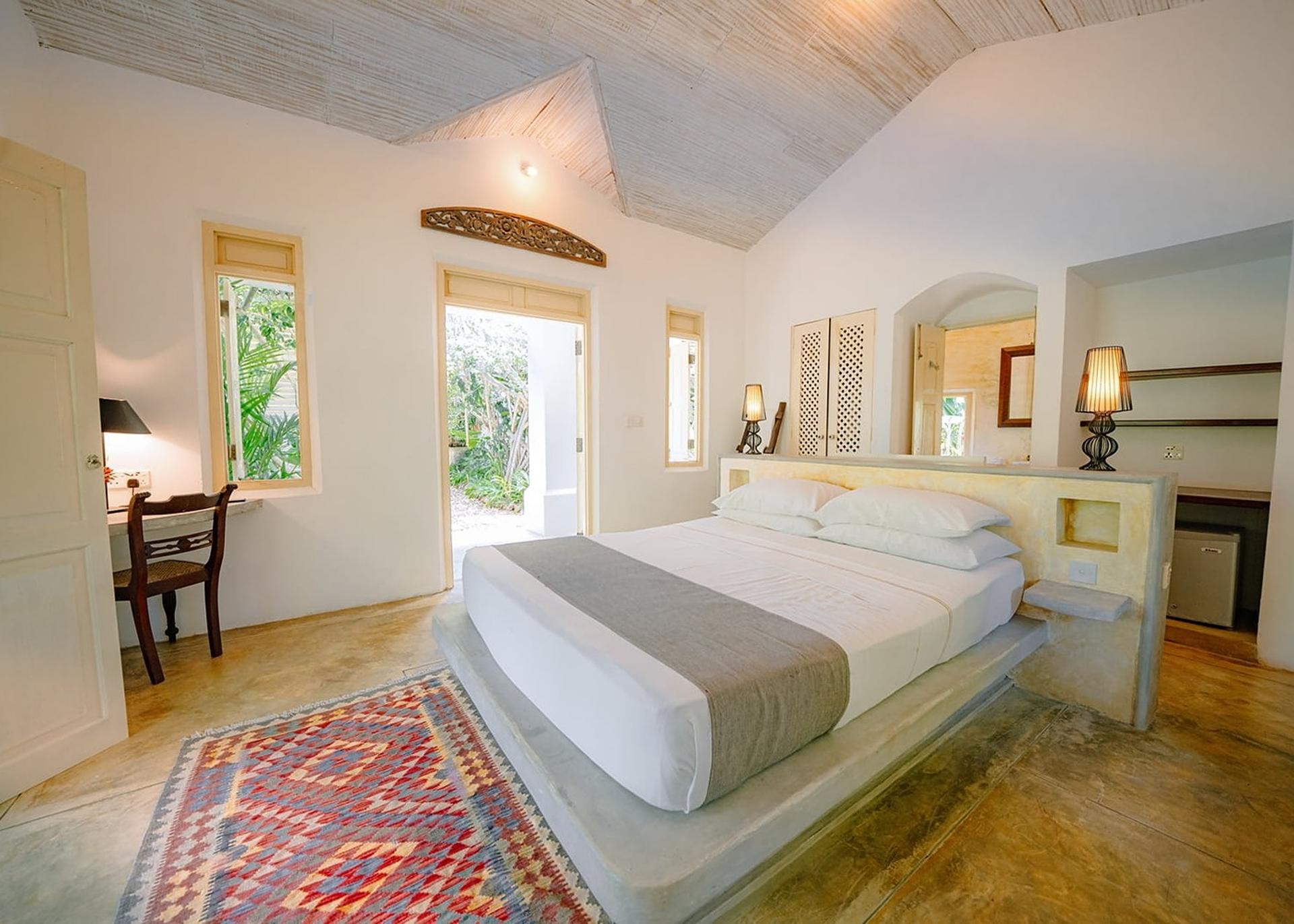 Rivers Edge bedroom with white king bed and woven rug