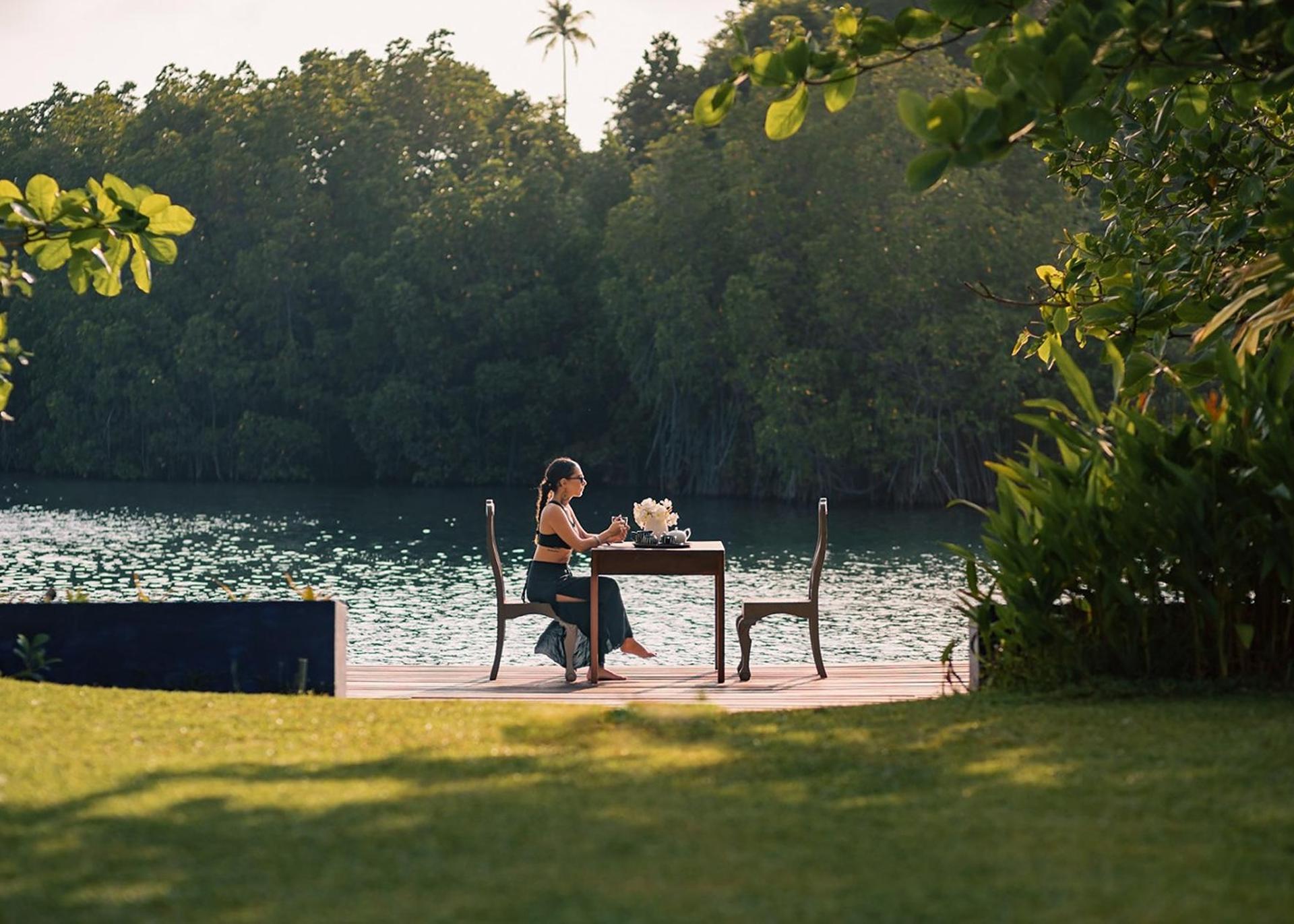 Couple dining alfresco at a lakeside table on the grounds of Casa Lago, Koggala, Sri Lanka