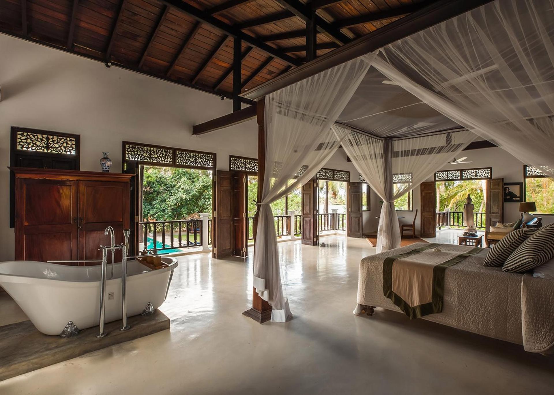 Master bedroom with wide timber floors, antique furnishings and garden outlook, Casa Lago, Koggala