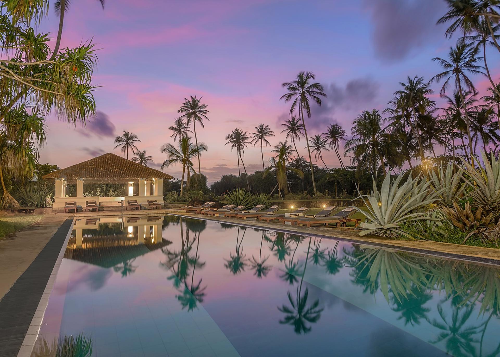 Heritage House Bentota pool at dusk under a vivid purple sky with palm silhouettes