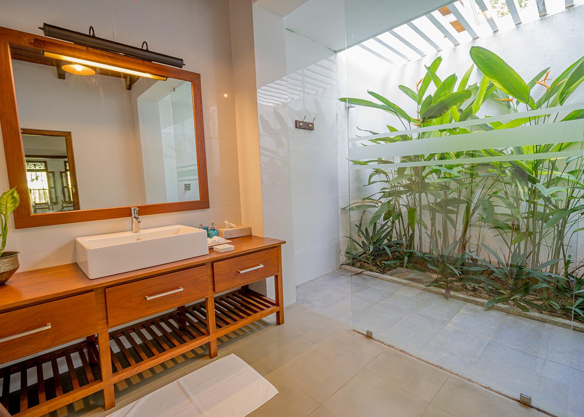 Bathroom with teak vanity and bamboo garden wall at Island Villa Ahangama, Ahangama