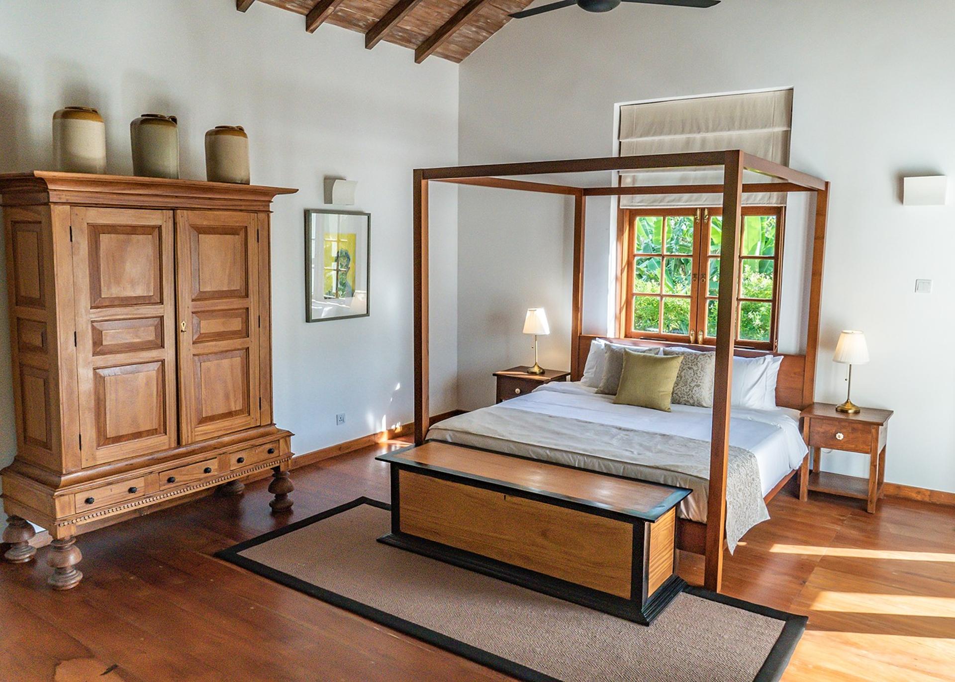 Master bedroom with four-poster bed and carved wardrobe at Island Villa Ahangama, Ahangama