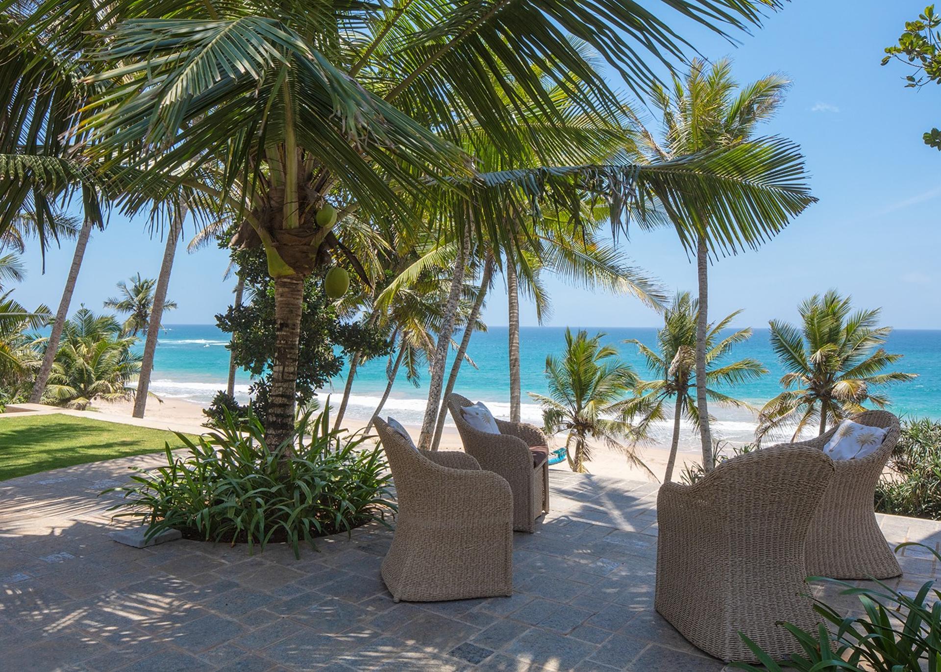 Beach seating area with chairs under palms facing Indian Ocean, Abiman Dickwella