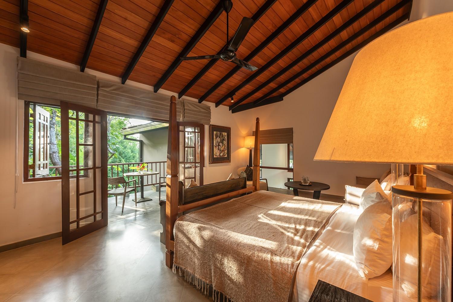 Villa four-poster bedroom with louvred windows and natural afternoon light