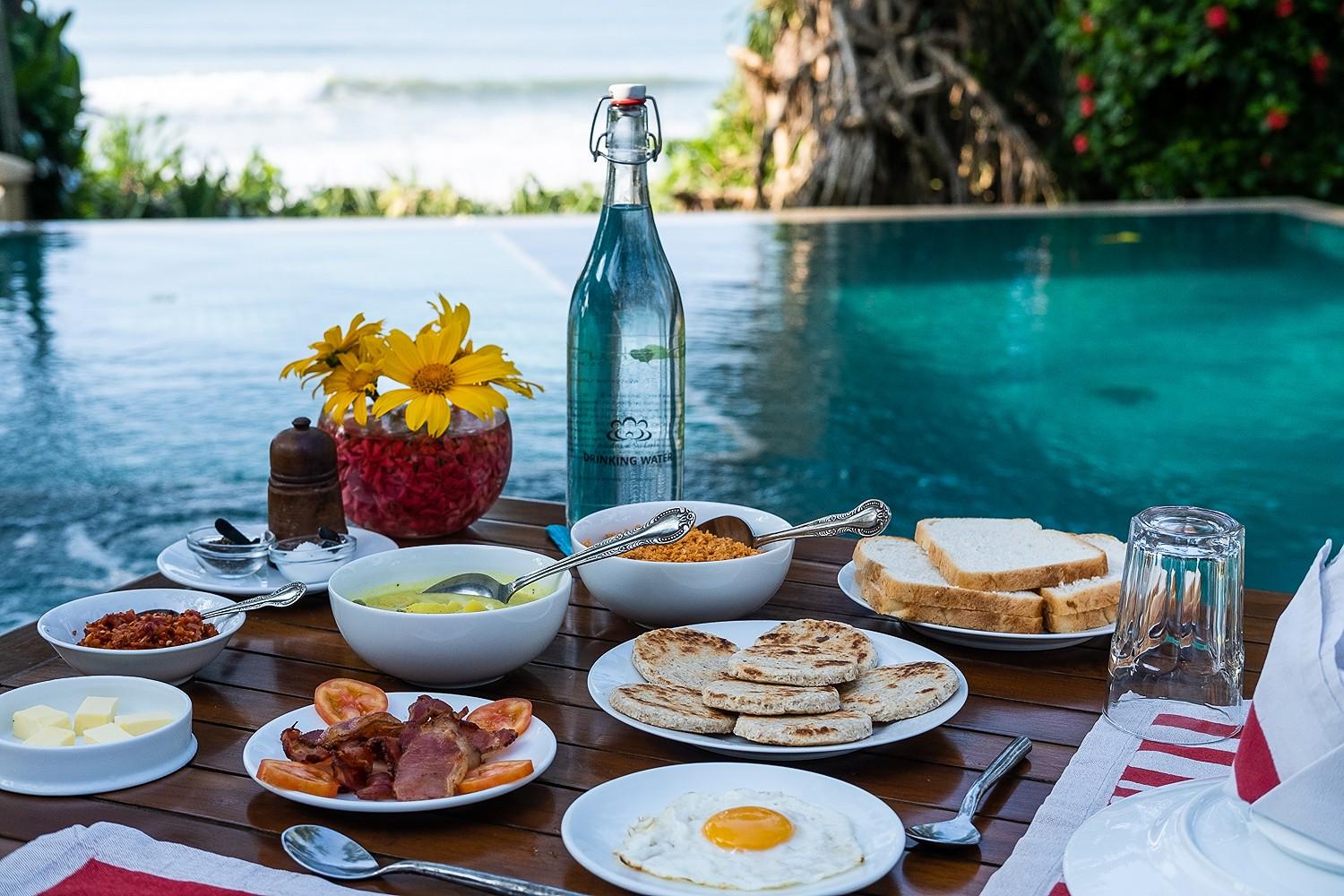 Matara villa outdoor dining by pool with breakfast spread and blue water