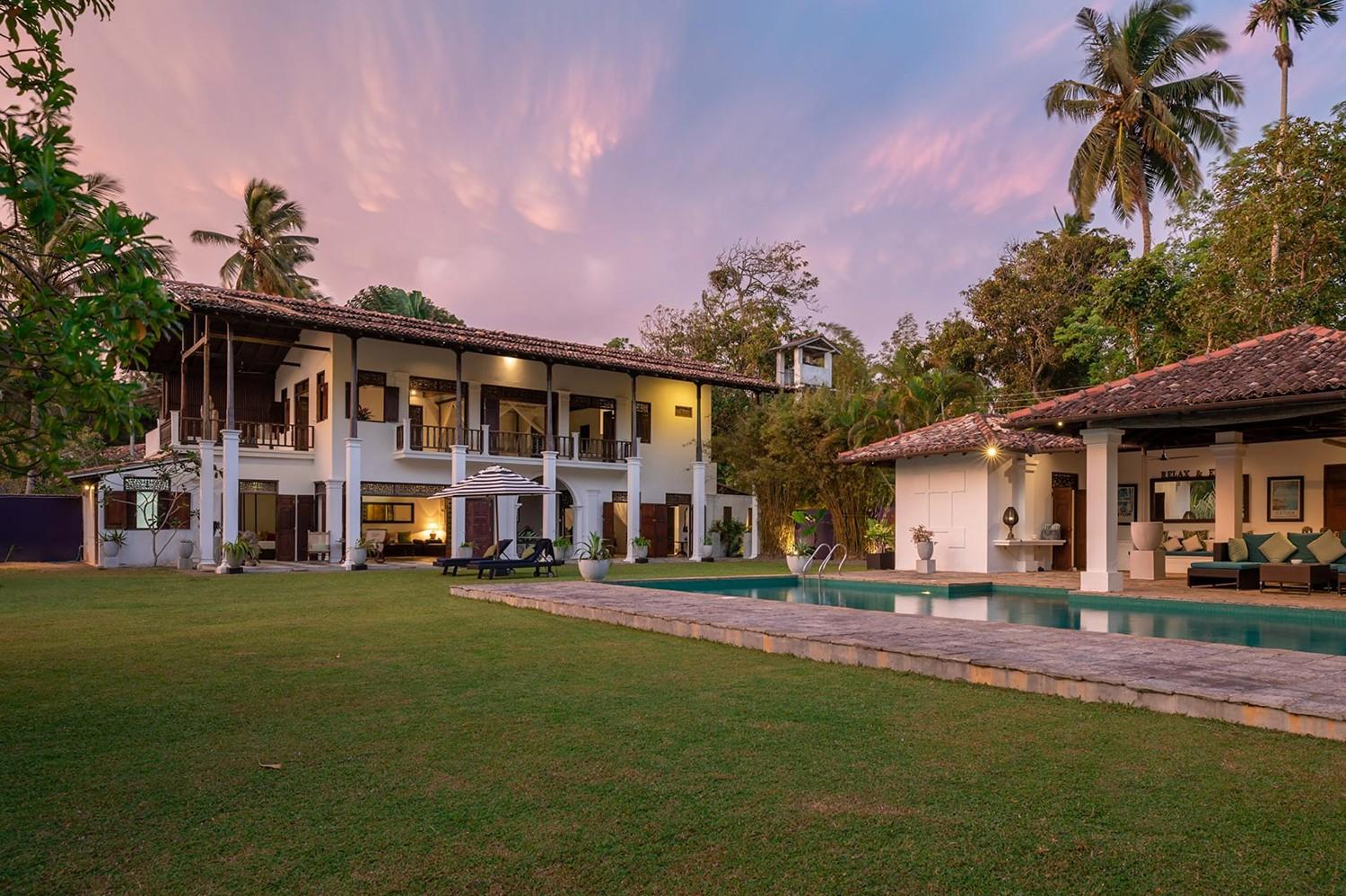 Casa Lago villa exterior under a vivid pink dusk sky reflected in the pool, Koggala, Sri Lanka