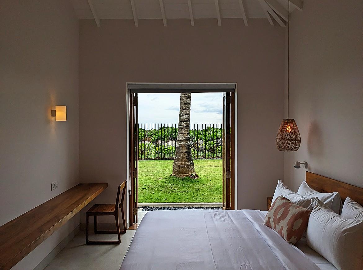 King bedroom with door open to tropical garden at Salt and Stone, Ahangama, Sri Lanka